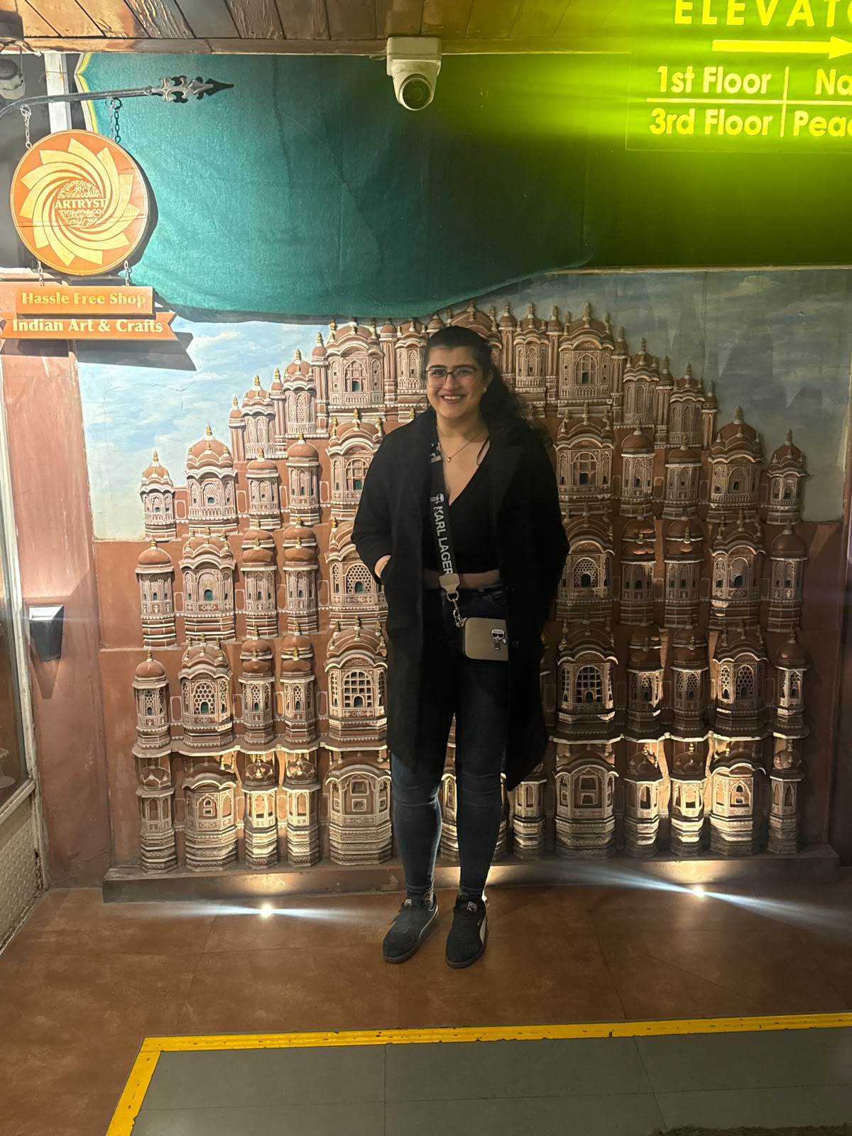 Simran smiling in front of a Jaipur mural